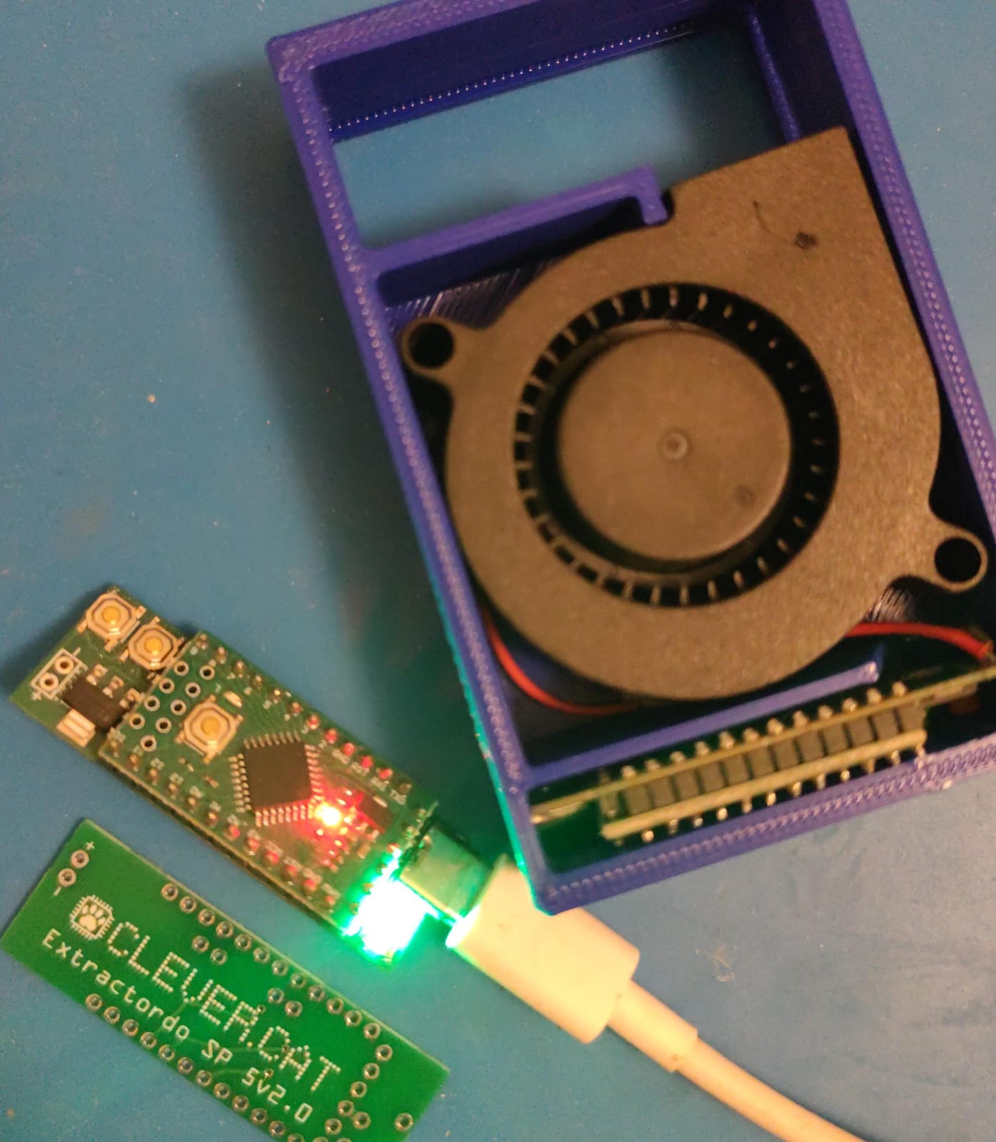 Extractordo, air extractor for a mushroom monotub: radial fan in a blue casing, control board with an LED and a board engraved CLEVER.CAT Extractordo, with a USB-C cable